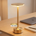 Lampe de bureau sans fil dorée MycoLamp posée sur un bureau épuré avec MacBook et carnet, sans aucun câble